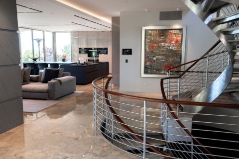 Home with curved stairway, kitchen, living space, and in-wall smart home touchscreen.