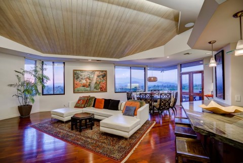 A living area with an open floor plan. Recessed and pendant lights illuminate the space.