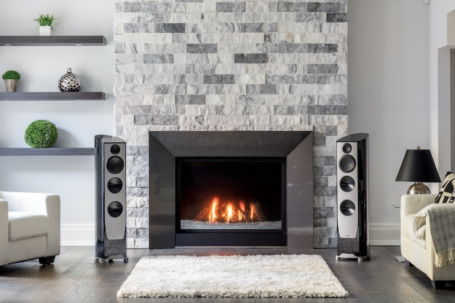  A pair of floor-standing speakers on either side of a fireplace in a living room.