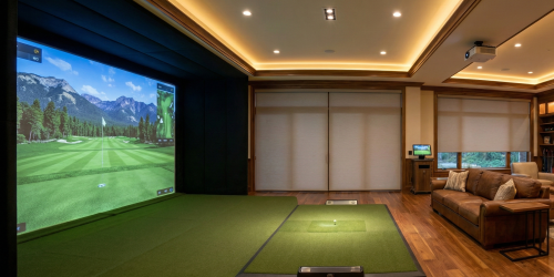 A luxurious indoor golf simulator room with a control panel and immersive screens.